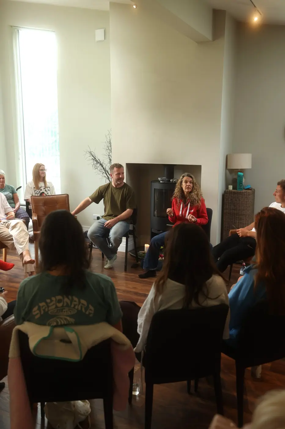 Pat in a circle of chairs with a group, listening as a participant speaks
