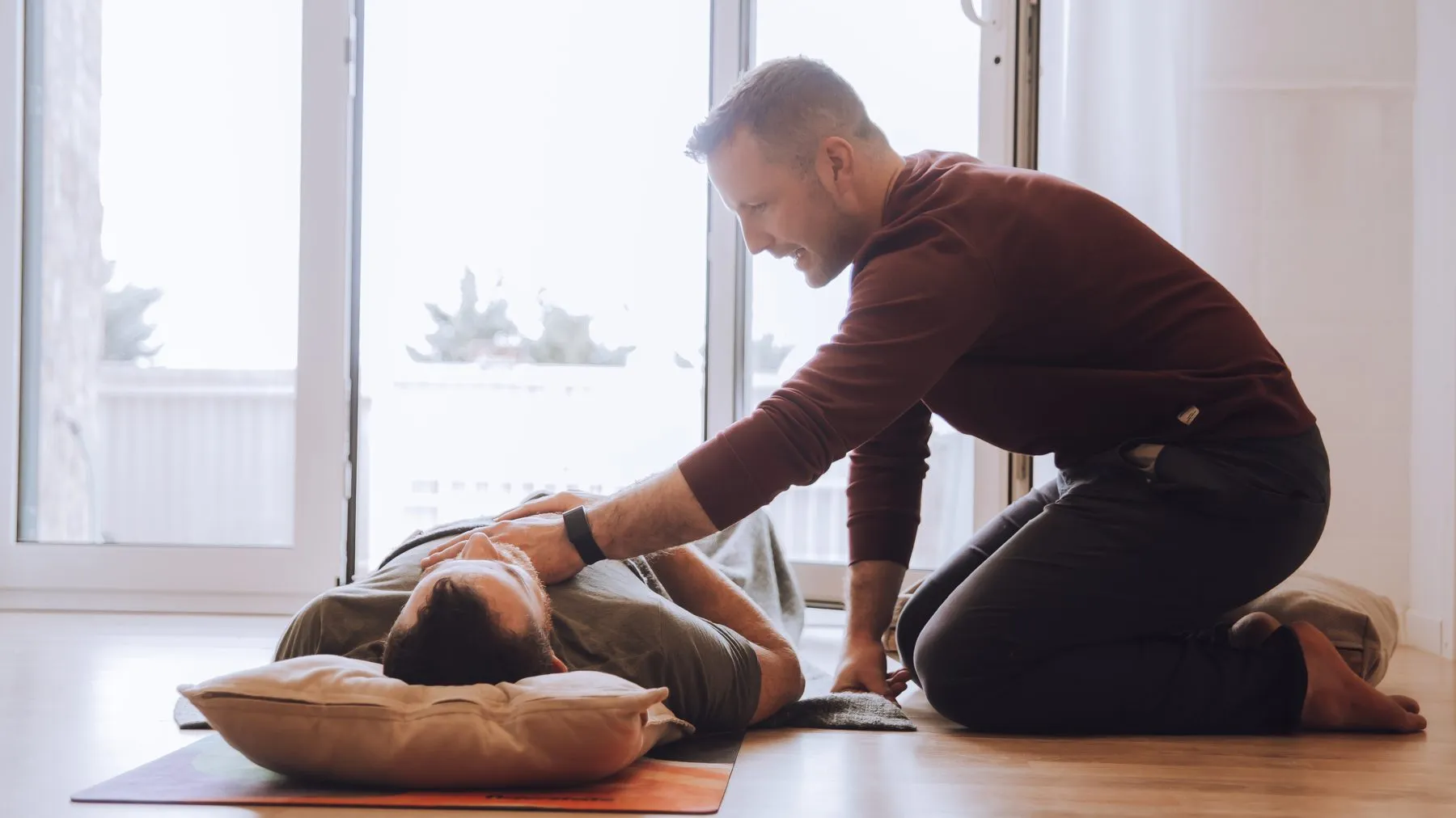 Pat working hands-on with a client lying on a mat