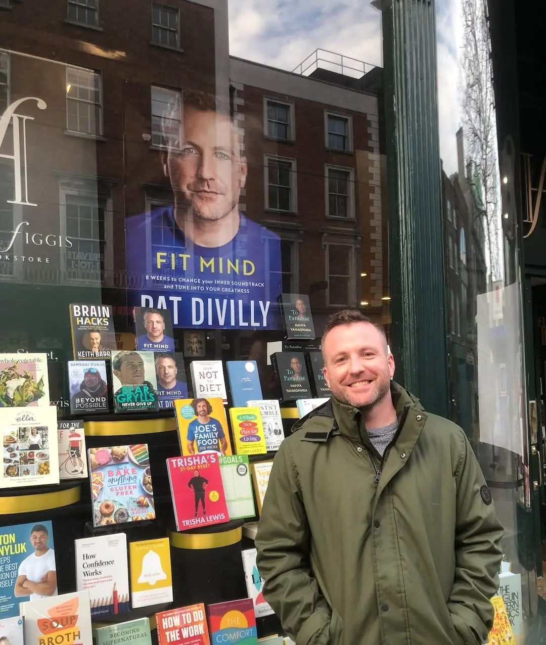 Pat smiling outside Hodges Figgis bookshop with a Fit Mind poster in the window