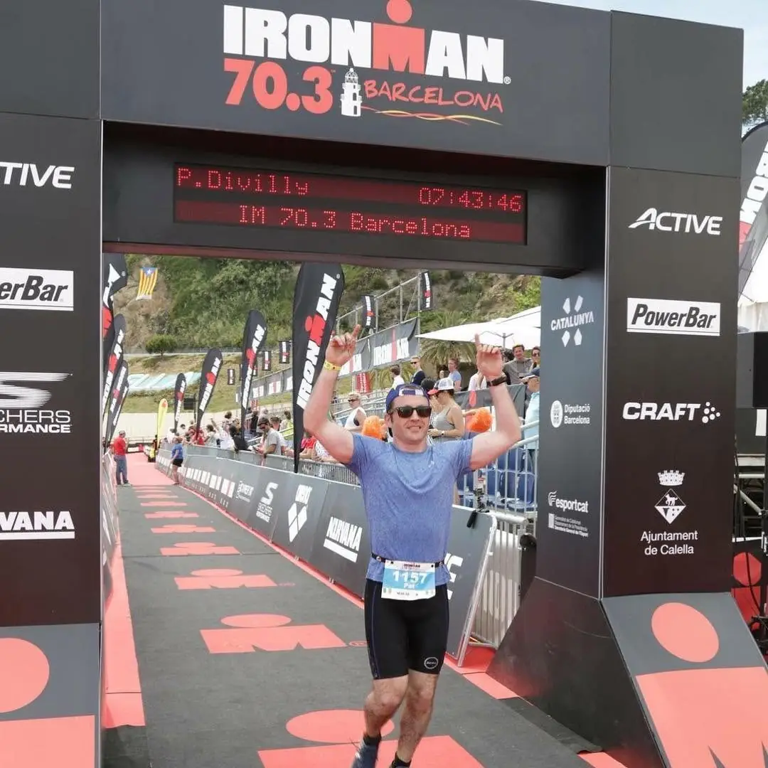 Pat crossing the finish line of Ironman 70.3 Barcelona with both arms raised