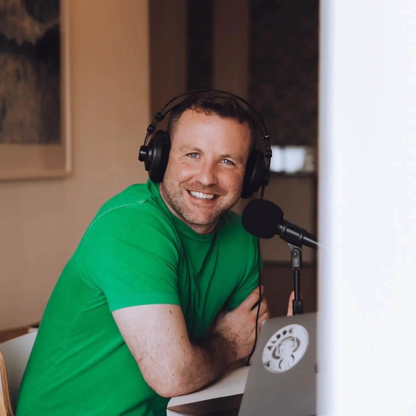 Pat smiling in headphones at a podcast microphone