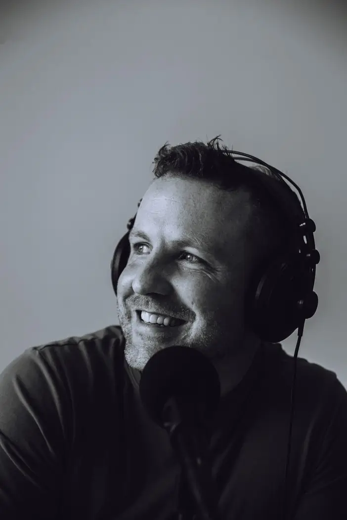Black and white portrait of Pat smiling at a microphone
