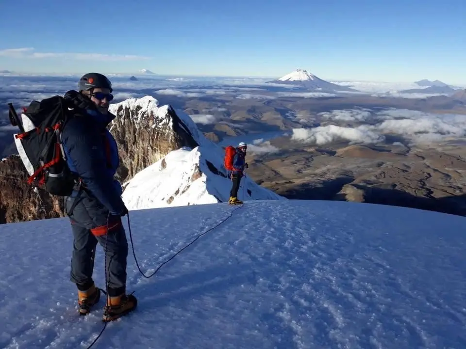 Pat roped up on a snowy summit ridge above the clouds