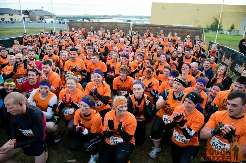 Hundreds of people in matching orange team T-shirts at the start of Tough Mudder